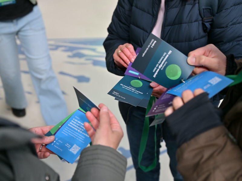 Handen van bezoekers van de conferentie die door hun badges bladeren